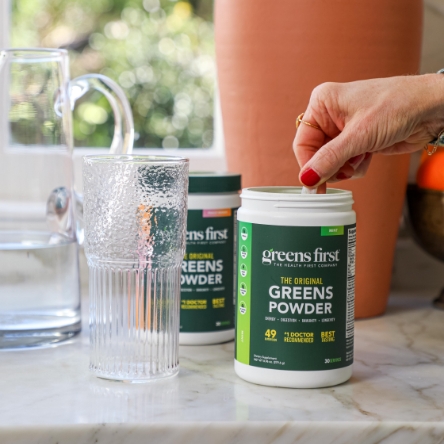 Hand stirring Greens First powder in a glass
